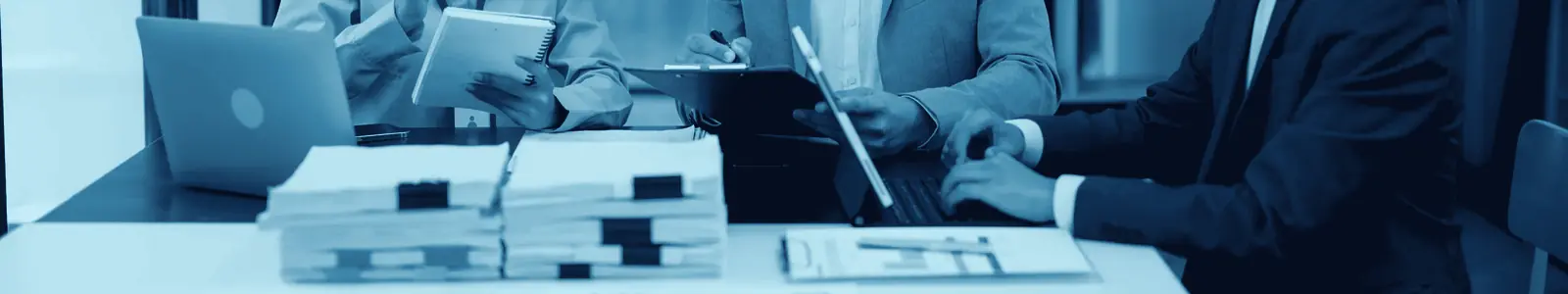 Un equipo trabajando alrededor de una mesa larga con documentos